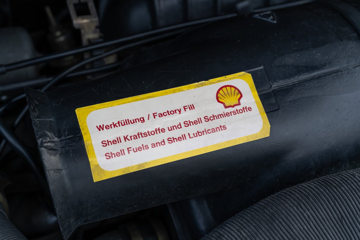 Close-up of a Shell "Factory Fill" sticker on the engine bay of a black 1976 Porsche 911S Sportomatic.