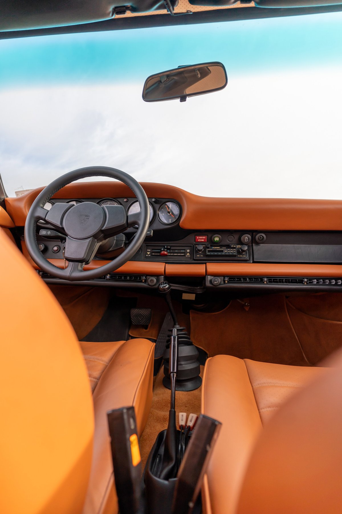 Black 1976 Porsche 911S Sportomatic interior with tan leather seats and dashboard trim.