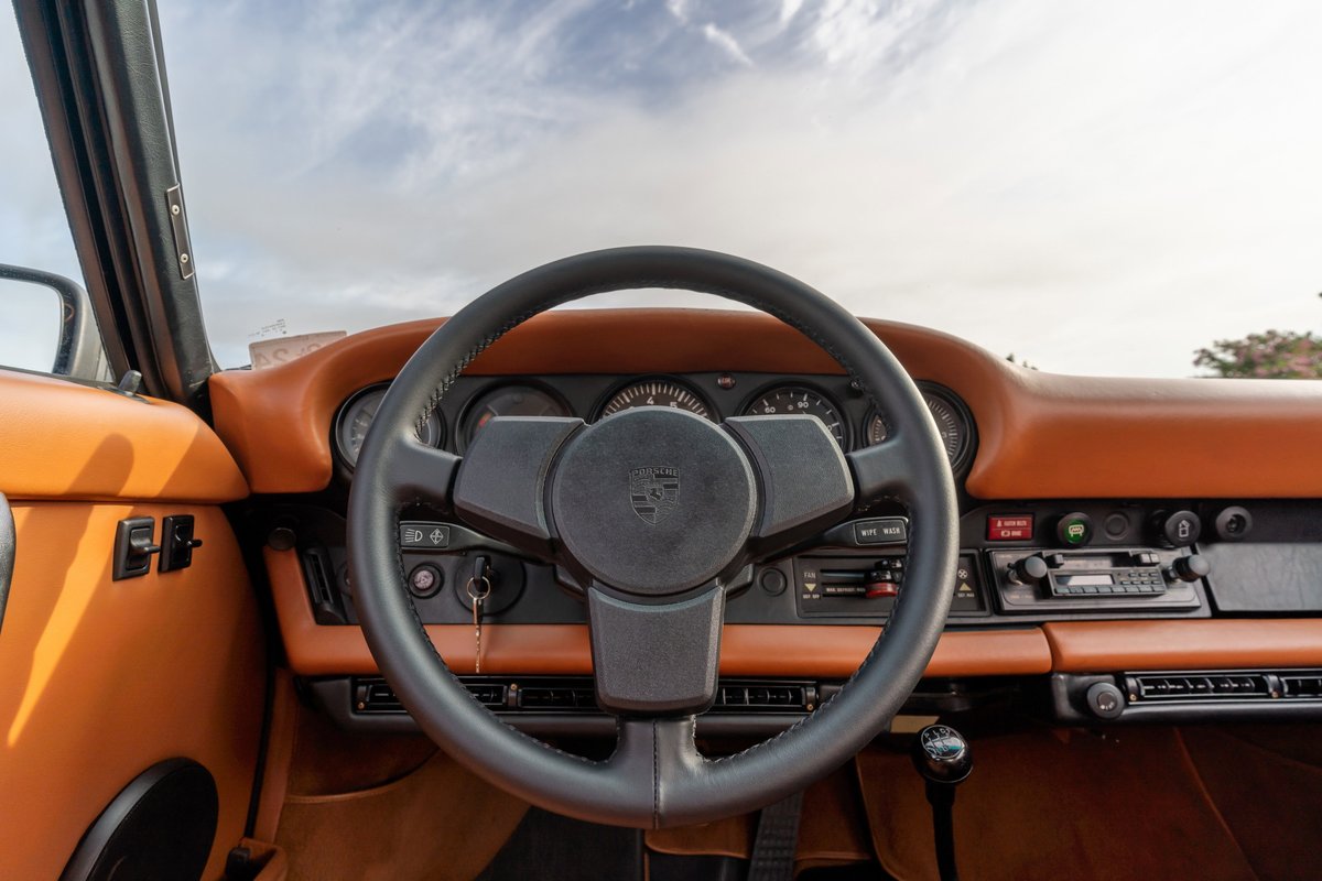 1976 Porsche 911S Sportomatic interior with tan leather trim, black steering wheel and dashboard.