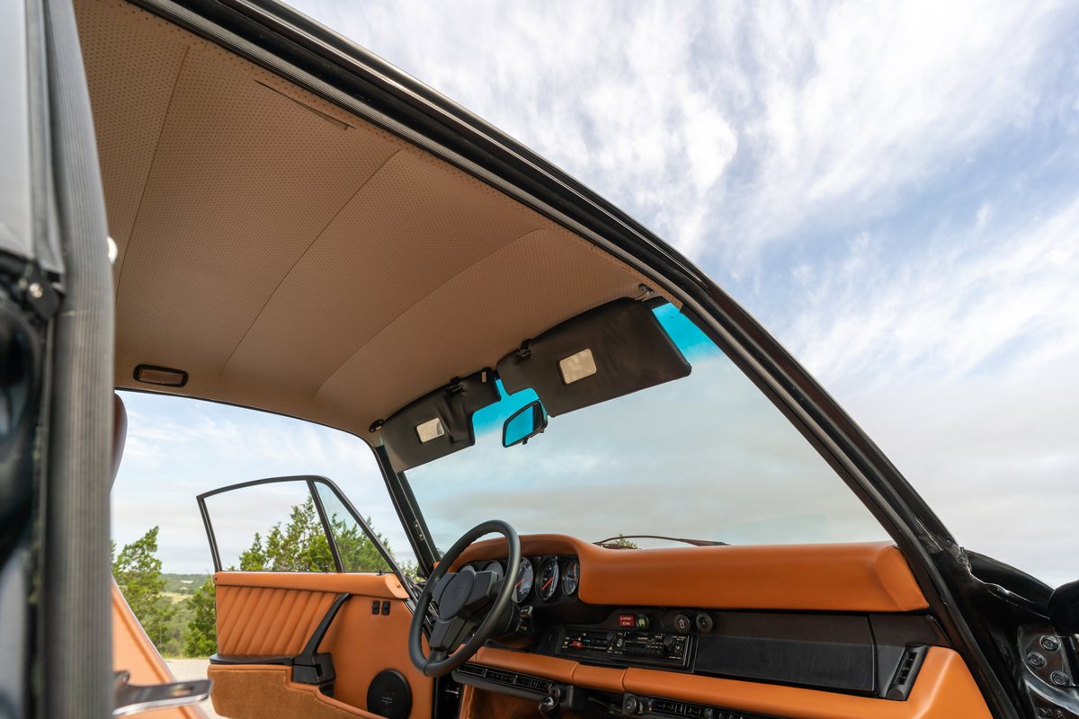 Interior of a black 1976 Porsche 911S Sportomatic, featuring tan leather upholstery and door panels.