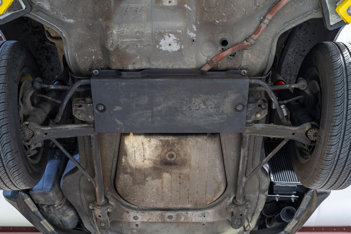 Underbody of a black 1976 Porsche 911S Sportomatic showing rear suspension and exhaust.