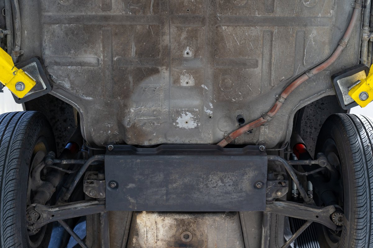 Underside of a black 1976 Porsche 911S Sportomatic with visible suspension and exhaust components.
