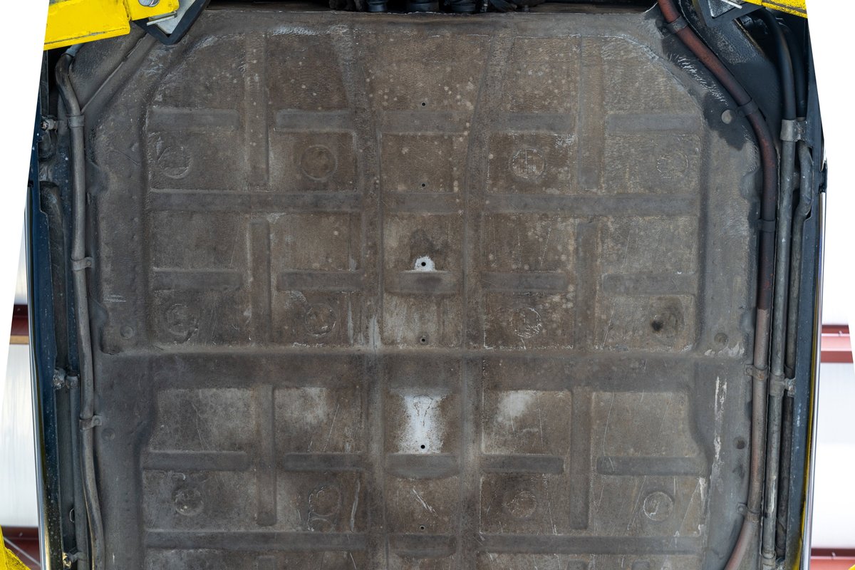 Underside of a black 1976 Porsche 911S Sportomatic showing the floor pan and exhaust system.