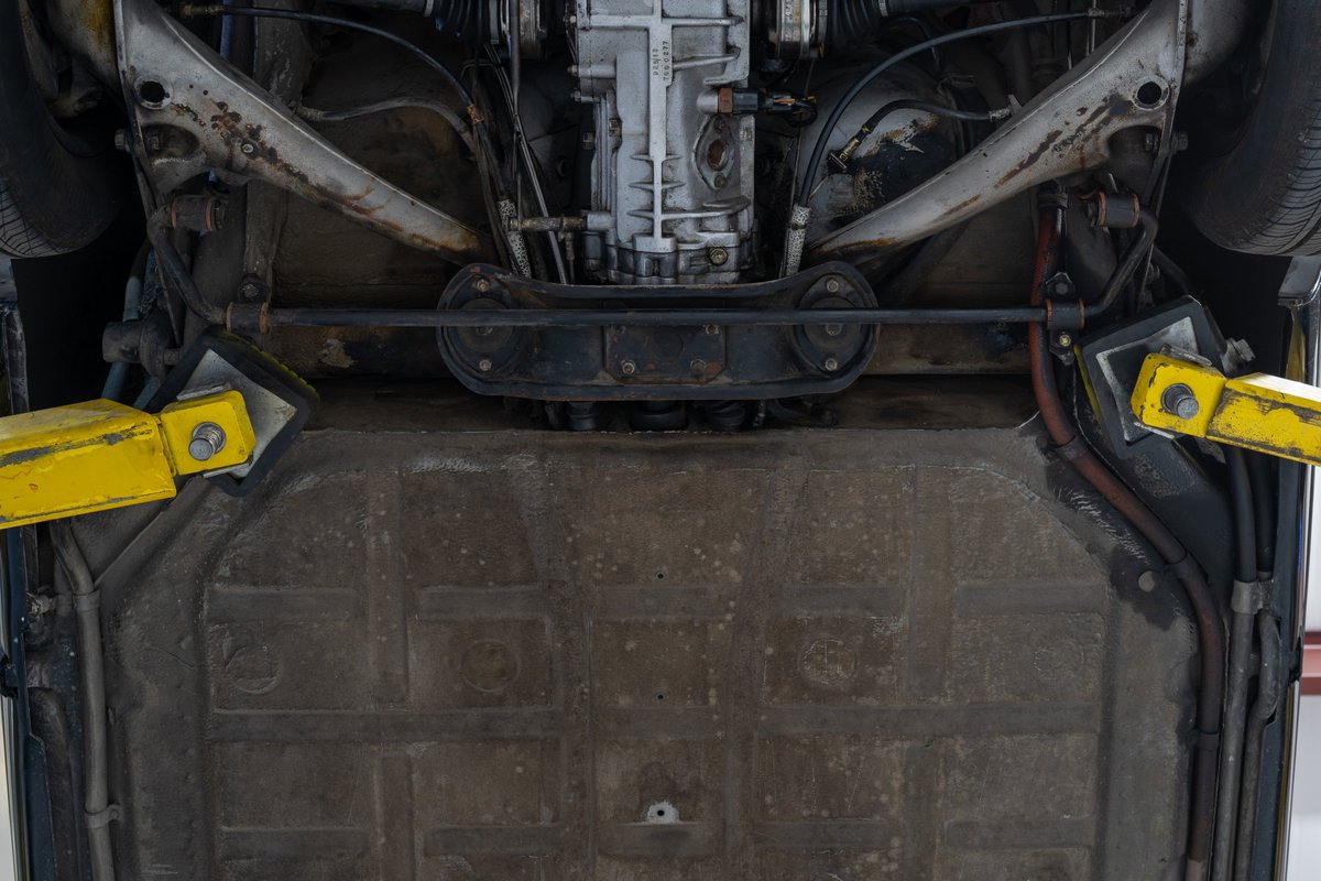 Underside of a black 1976 Porsche 911S Sportomatic on a lift, showing suspension and transmission.