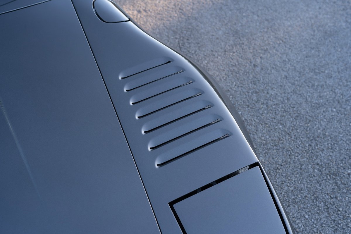 Close up on dark grey 1989 Porsche 930 Turbo Flachbau hood vents and headlight.