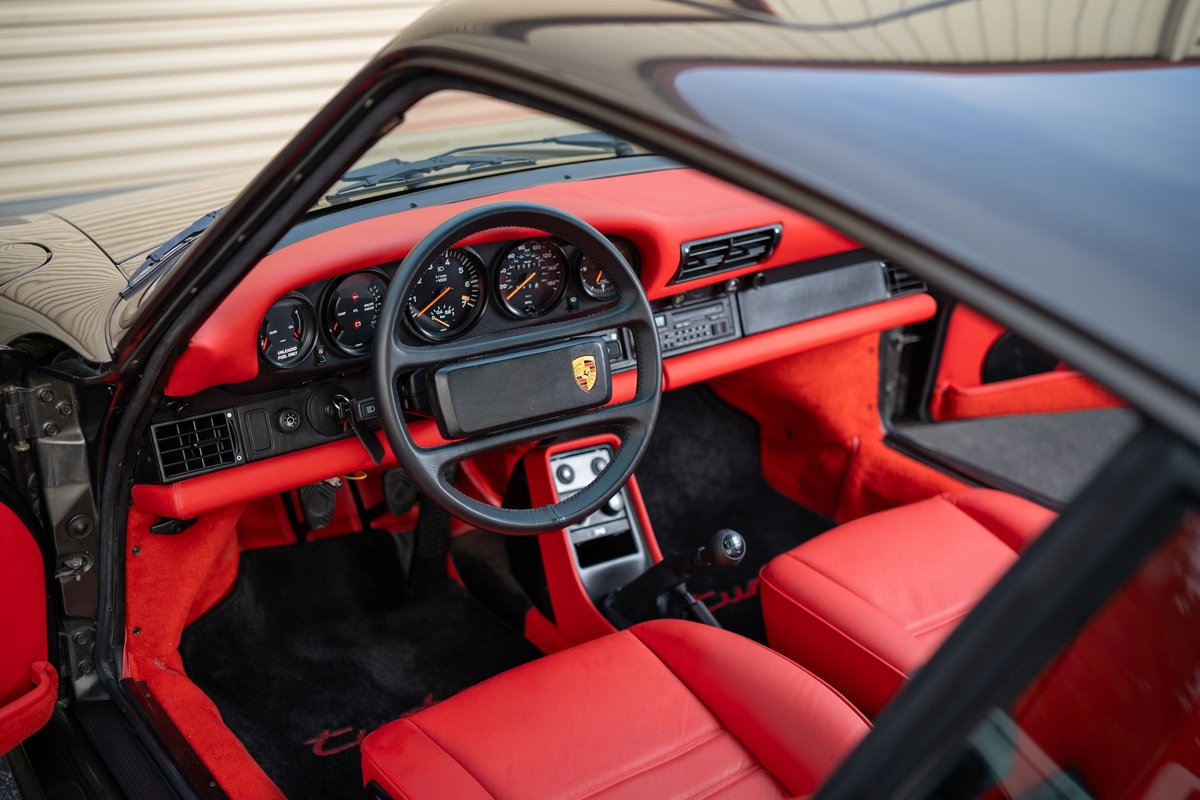 Black 1989 Porsche 930 Turbo Flachbau interior with red leather seats and carpeting.