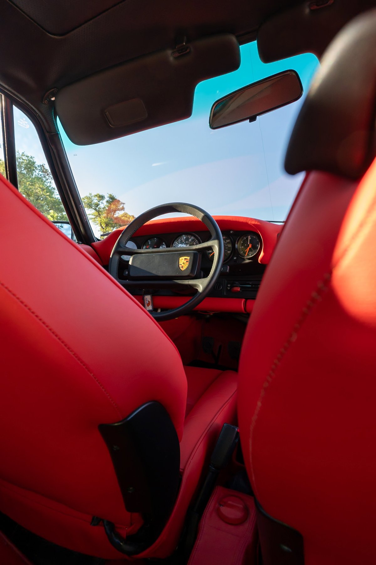 Interior of a 1989 Porsche 930 Turbo Flachbau with red leather seats, steering wheel, and dashboard trim.