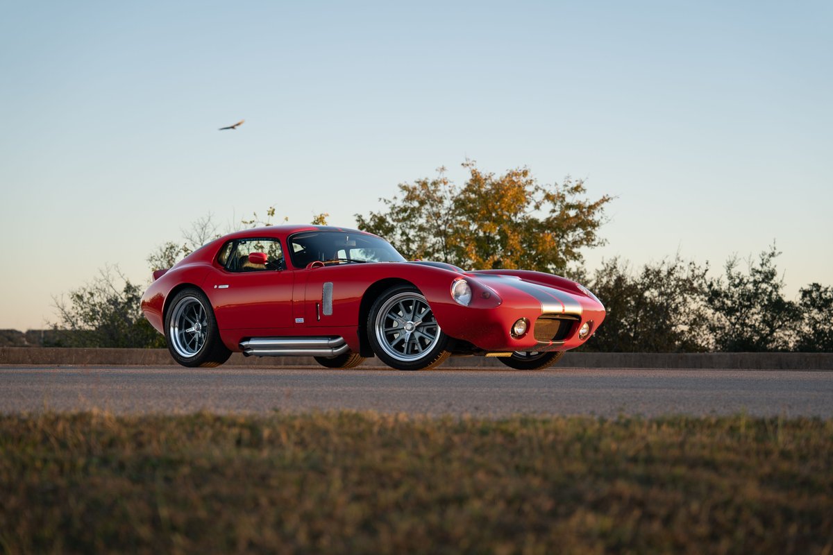 Monza Red 1965 Superformance Shelby Daytona CSX with racing stripes, side pipes, and polished rims.