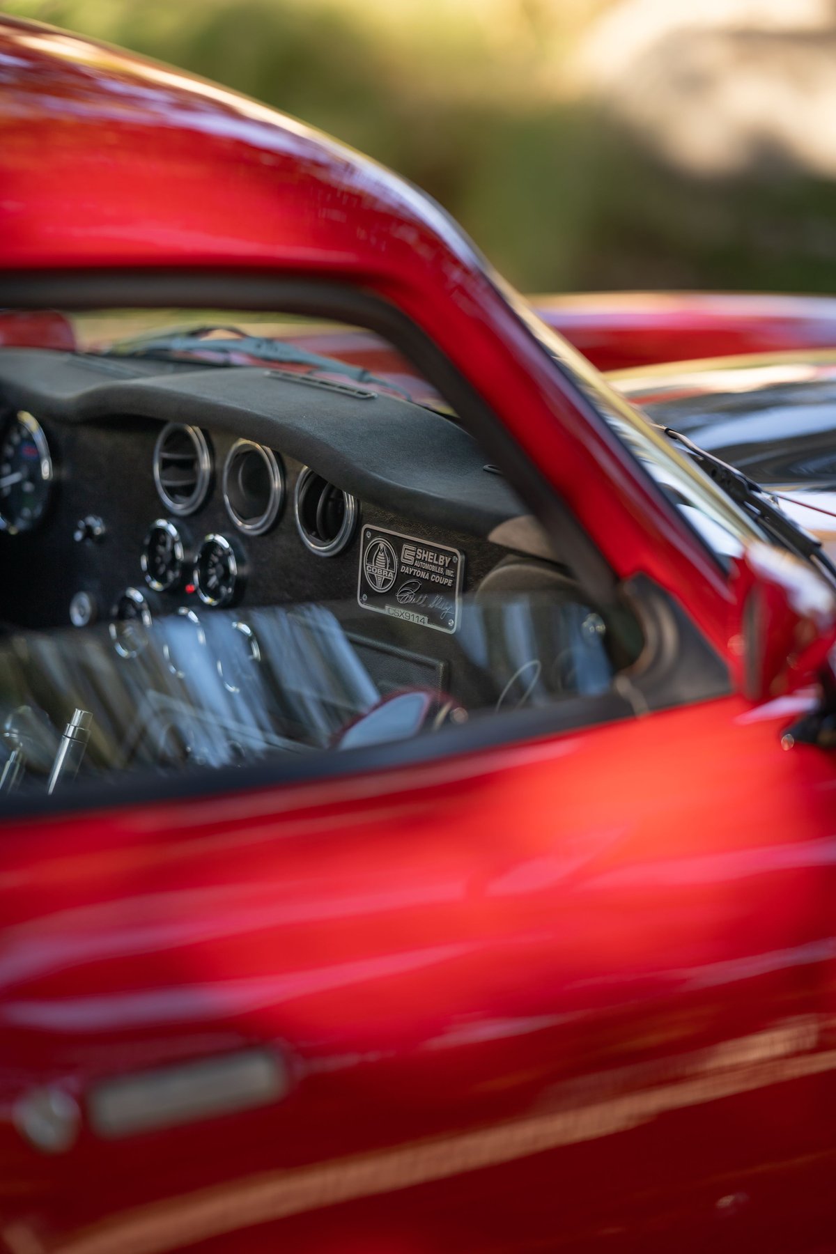 Red 1965 Superformance Shelby Daytona Coupe interior with Shelby plaque and gauges.