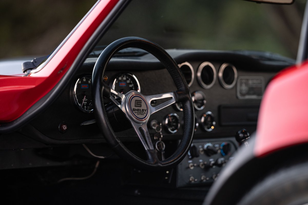 Interior shot of a red 1965 Superformance Shelby Daytona coupe with a Shelby steering wheel.
