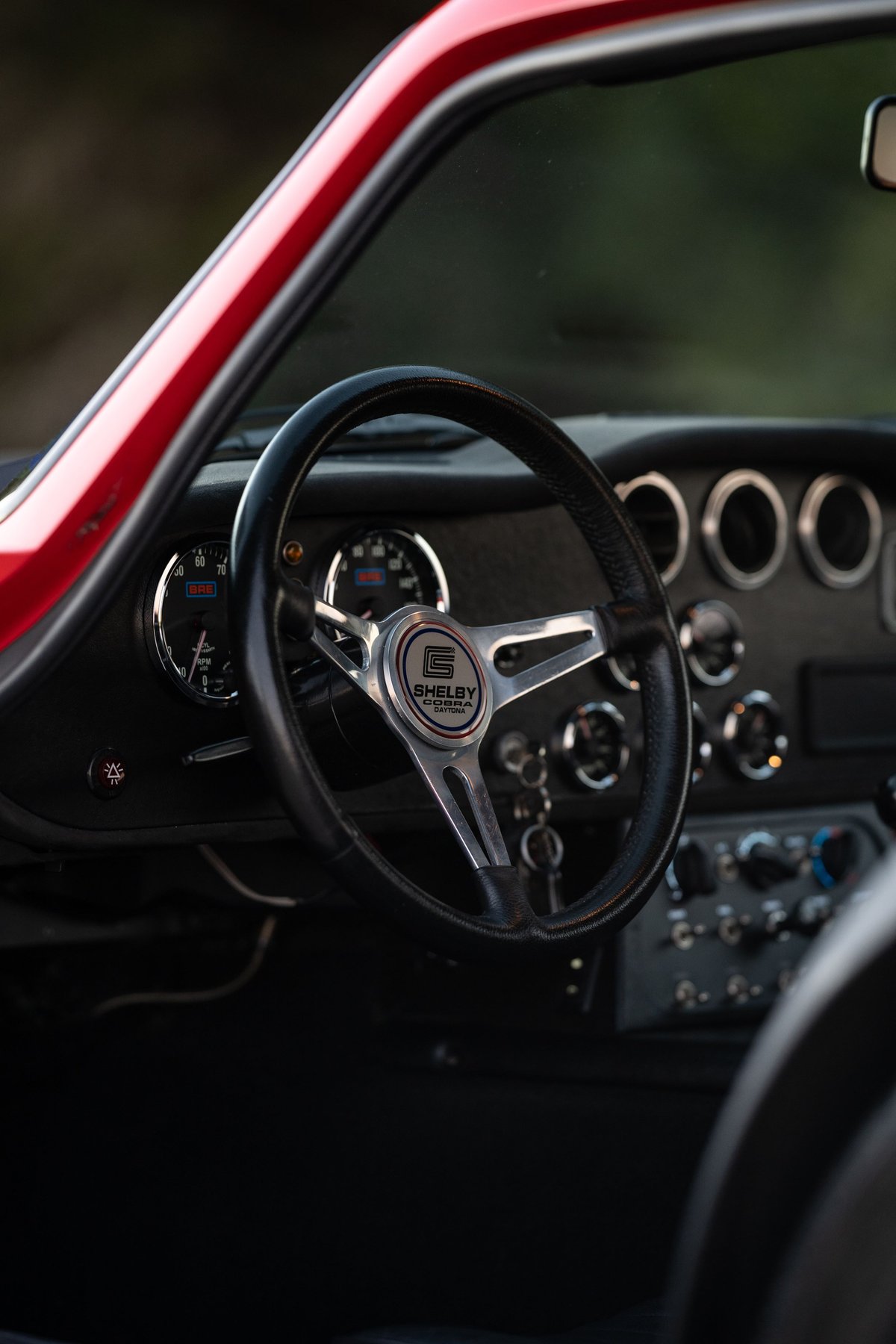 Close-up of a red 1965 Superformance Shelby Daytona CSX steering wheel and dashboard.