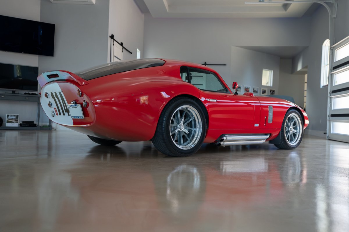 Red 1965 Superformance Shelby Daytona CSX with white stripe livery on the tail section and silver alloy rims.