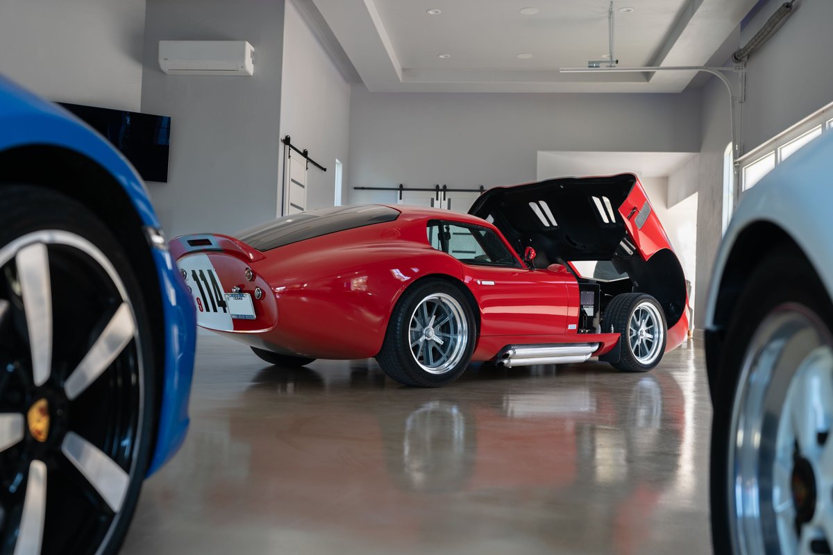 Monza Red 1965 Superformance Shelby Daytona CSX with hood open, showing silver rims and side pipes.