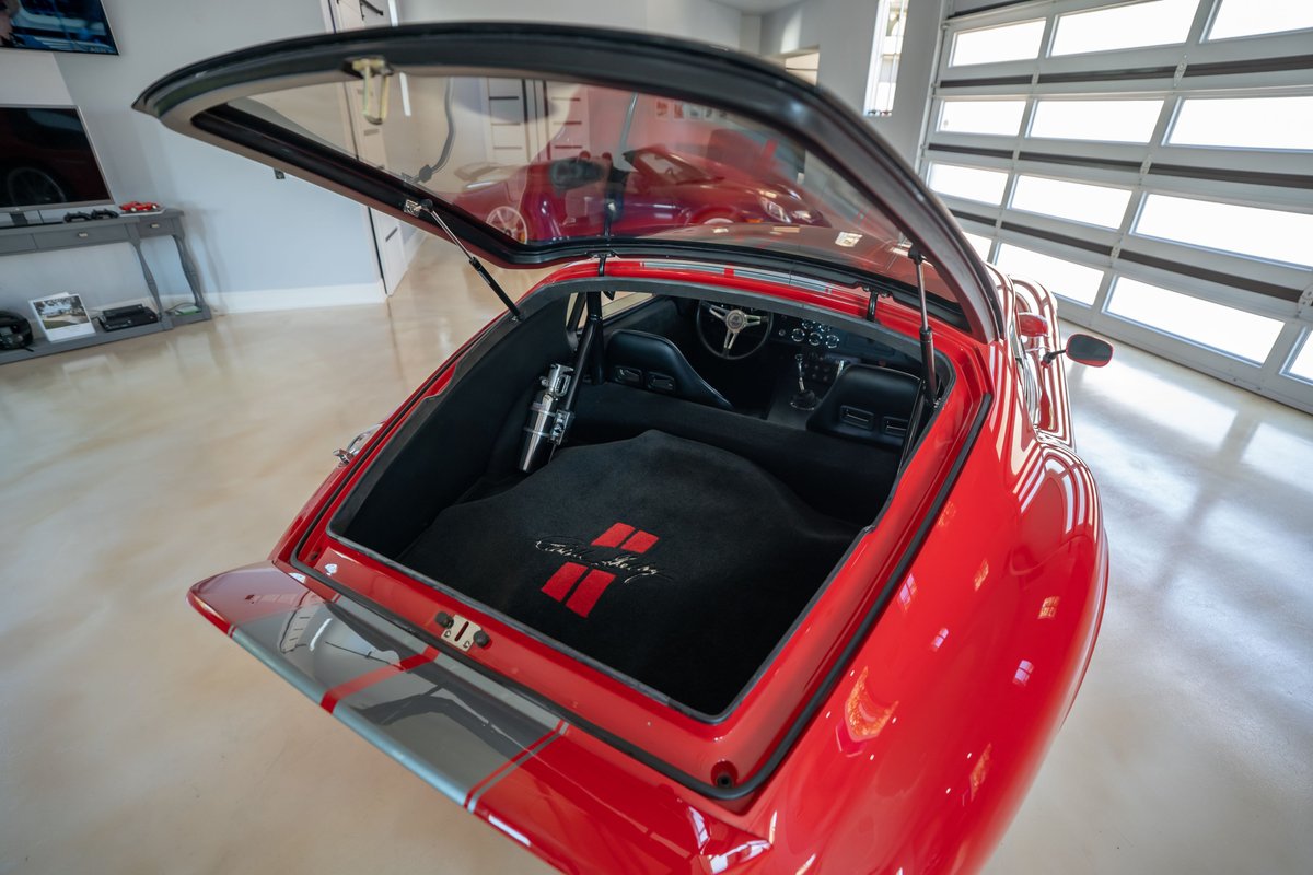 Red 1965 Superformance Shelby Daytona CSX coupe with grey racing stripes and a visible interior.