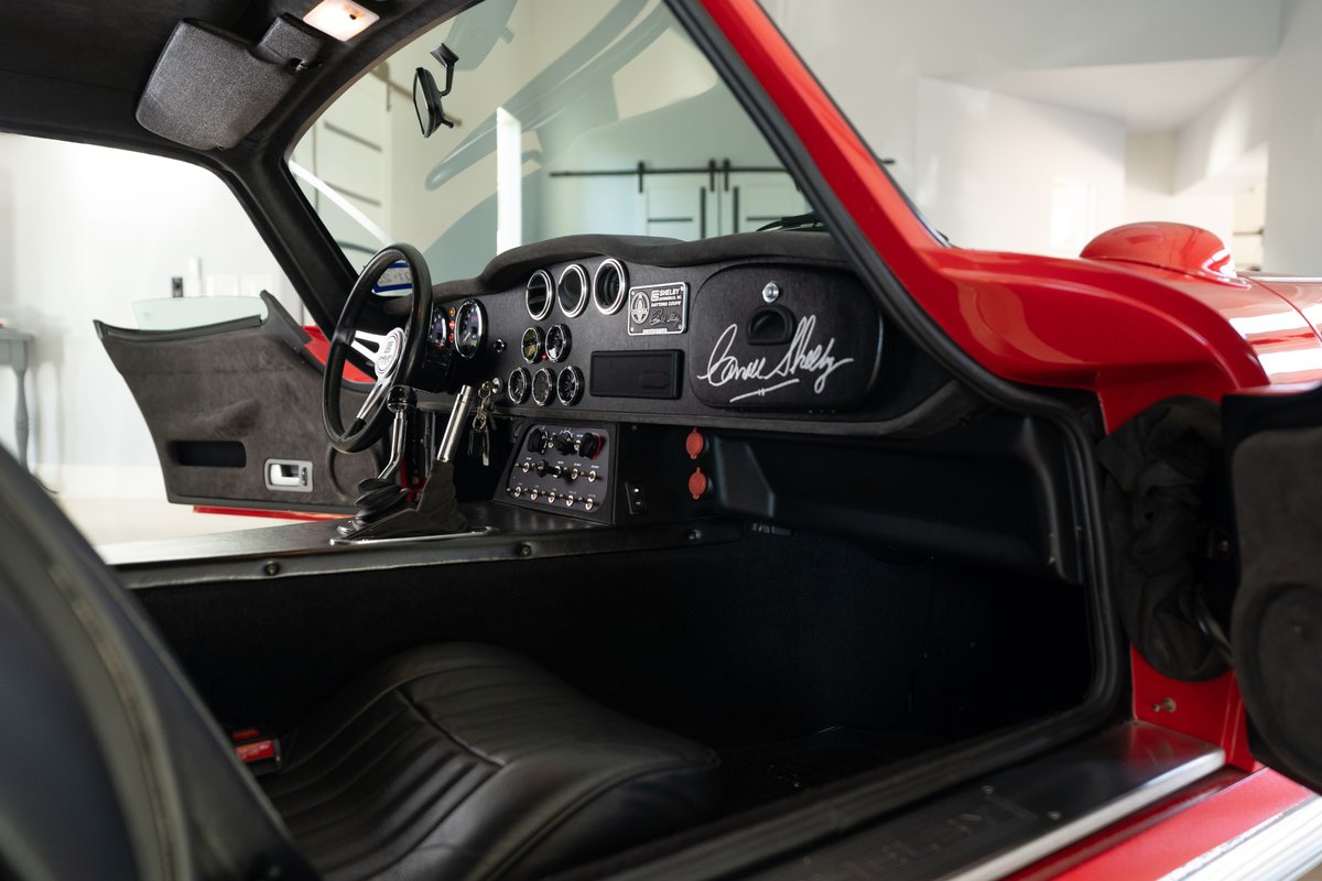 Interior of a red 1965 Superformance Shelby Daytona CSX with a leather dash & Carroll Shelby's signature.