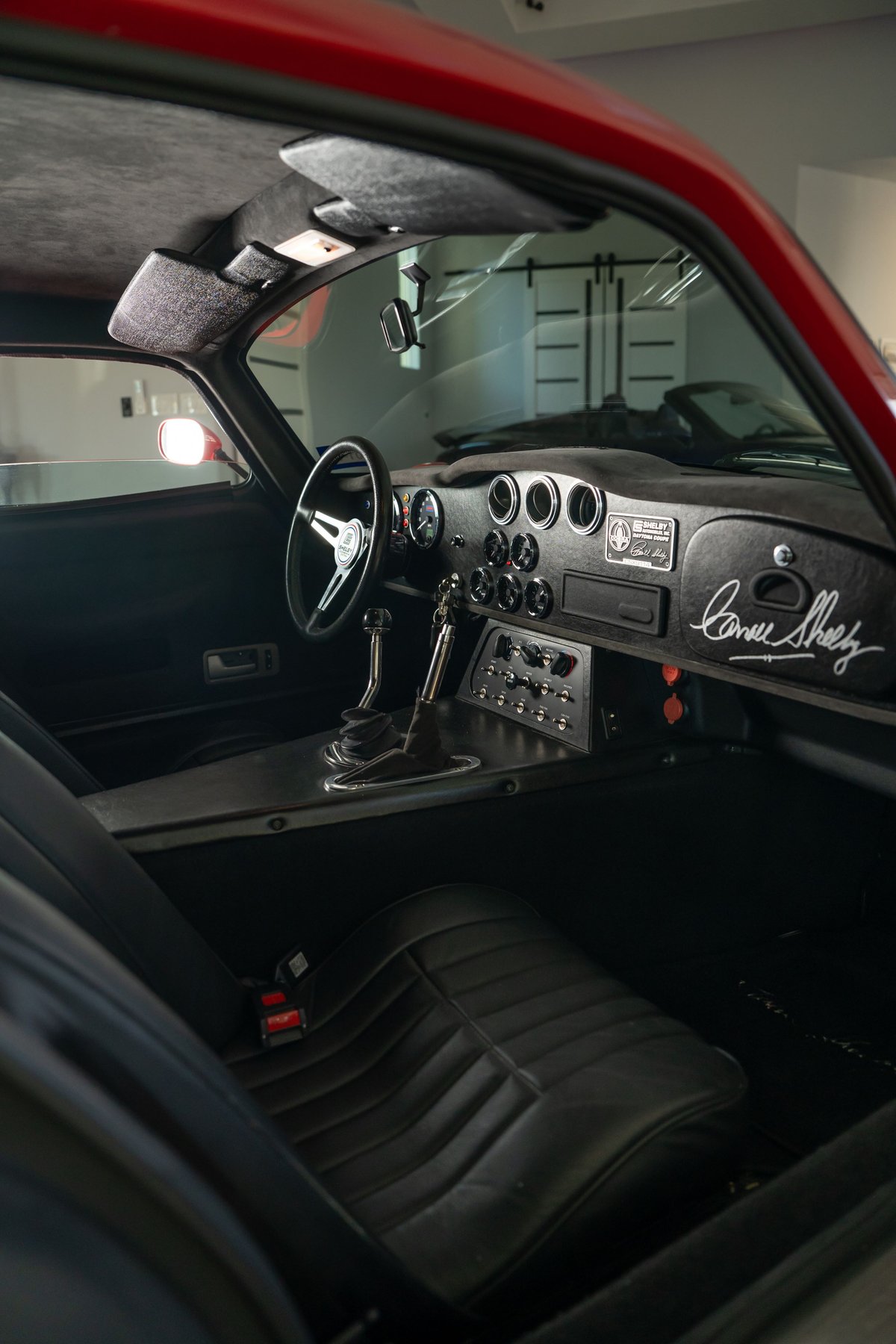Red 1965 Superformance Shelby Daytona CSX interior with a leather seat, shifter, and signed dashboard.