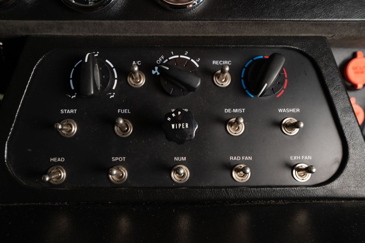 Interior dashboard of a 1965 Shelby Daytona Coupe replica, featuring toggle switches and rotary knobs for various functions.