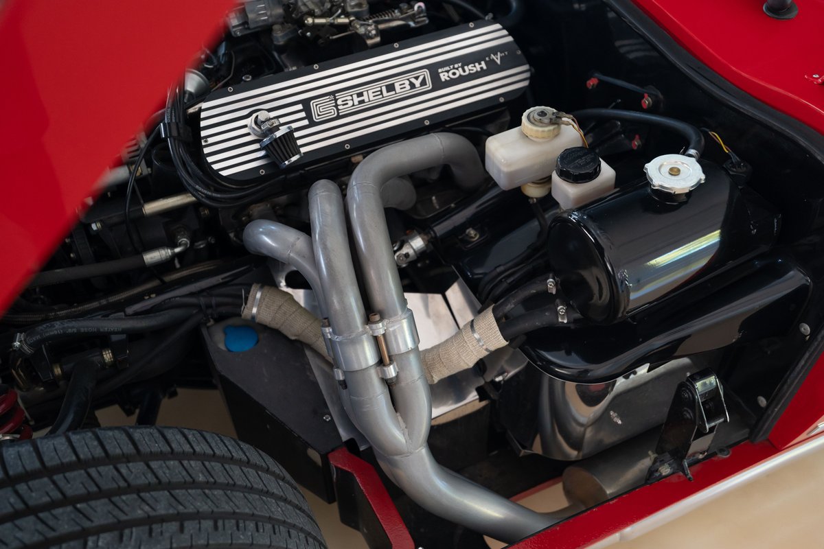 Red 1965 Superformance Shelby Daytona Coupe engine bay, Roush V-engine, chrome exhaust headers, shiny black reservoirs.