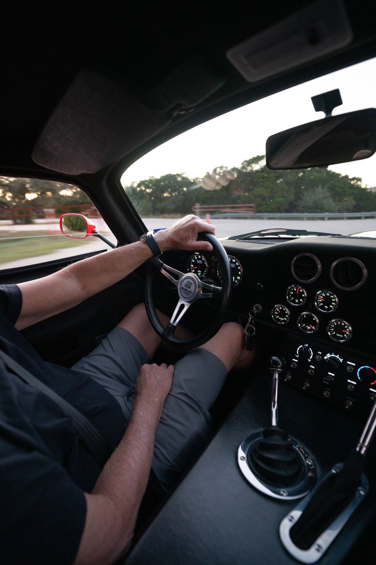 Driver's view of a red 1965 Superformance Shelby Daytona Coupe interior with a banjo steering wheel & shifter.
