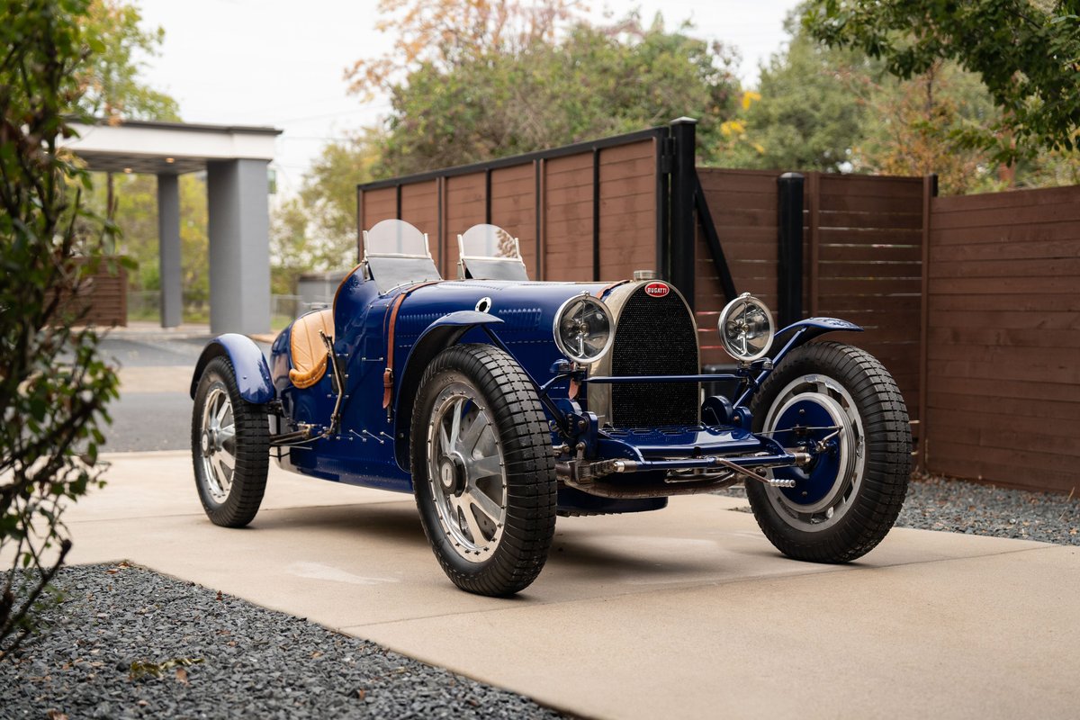 1927 blue Pur Sang Bugatti Type 35 race car with tan leather seats and chrome rims.