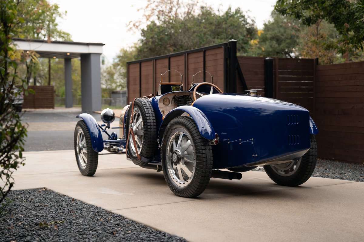 Rear view of a blue 1927 Pur Sang Bugatti Type 35 with wire-spoke rims and dual spare tires.