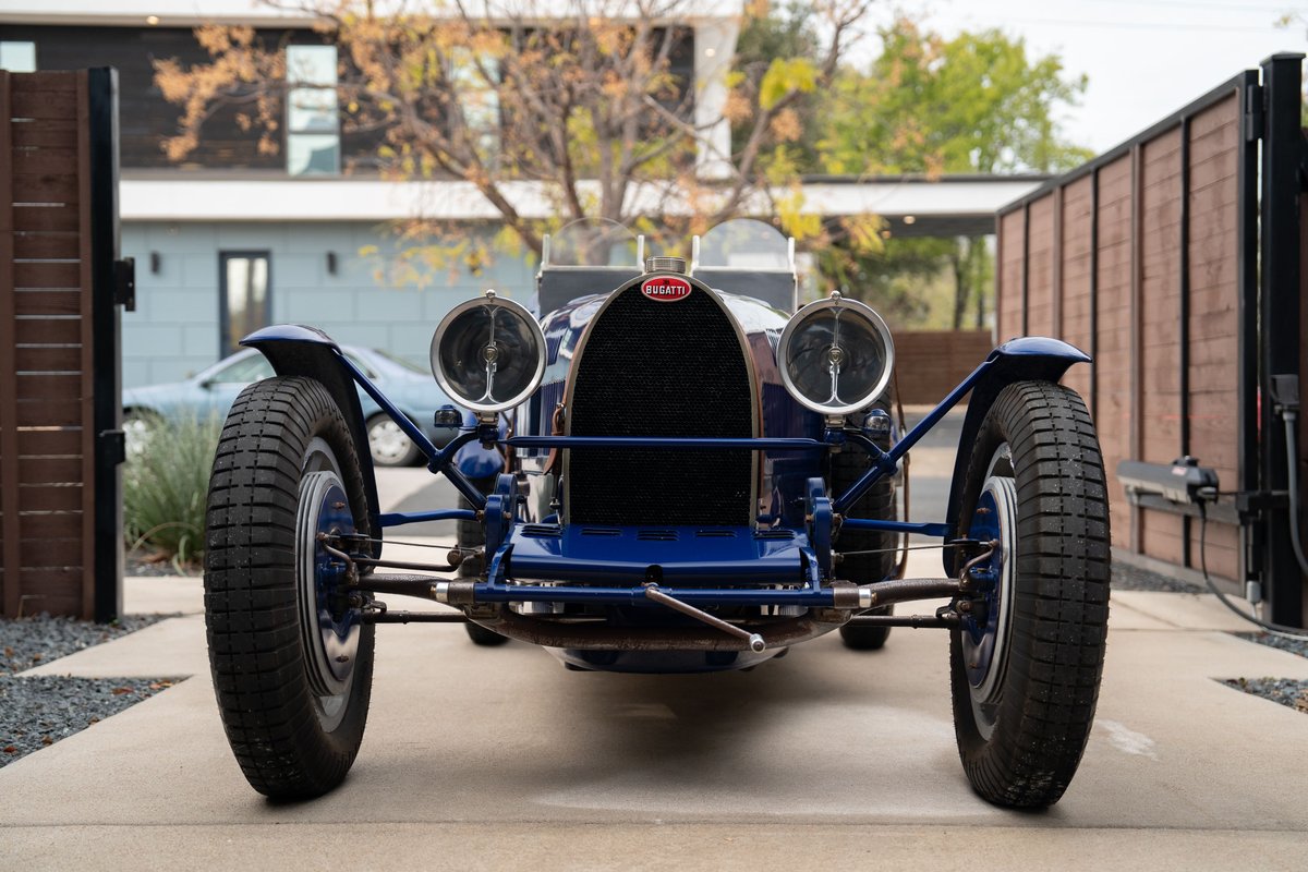Front view of a blue 1927 Bugatti Type 35 Pur Sang with chrome rims and dual headlights.