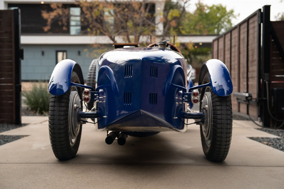 Rear view of a vintage blue 1927 Pur-Sang Bugatti Type 35 with spoked rims and a polished grille.