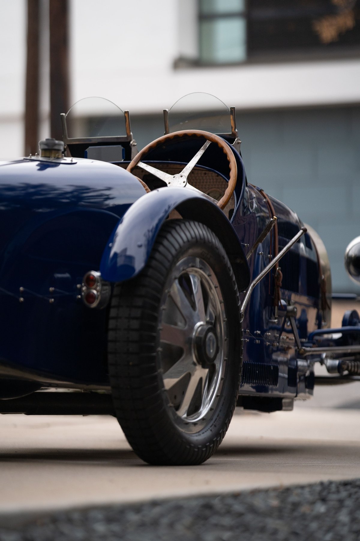 Classic blue 1927 Bugatti Type 35 race car, featuring a wooden steering wheel and wire-spoke rims.