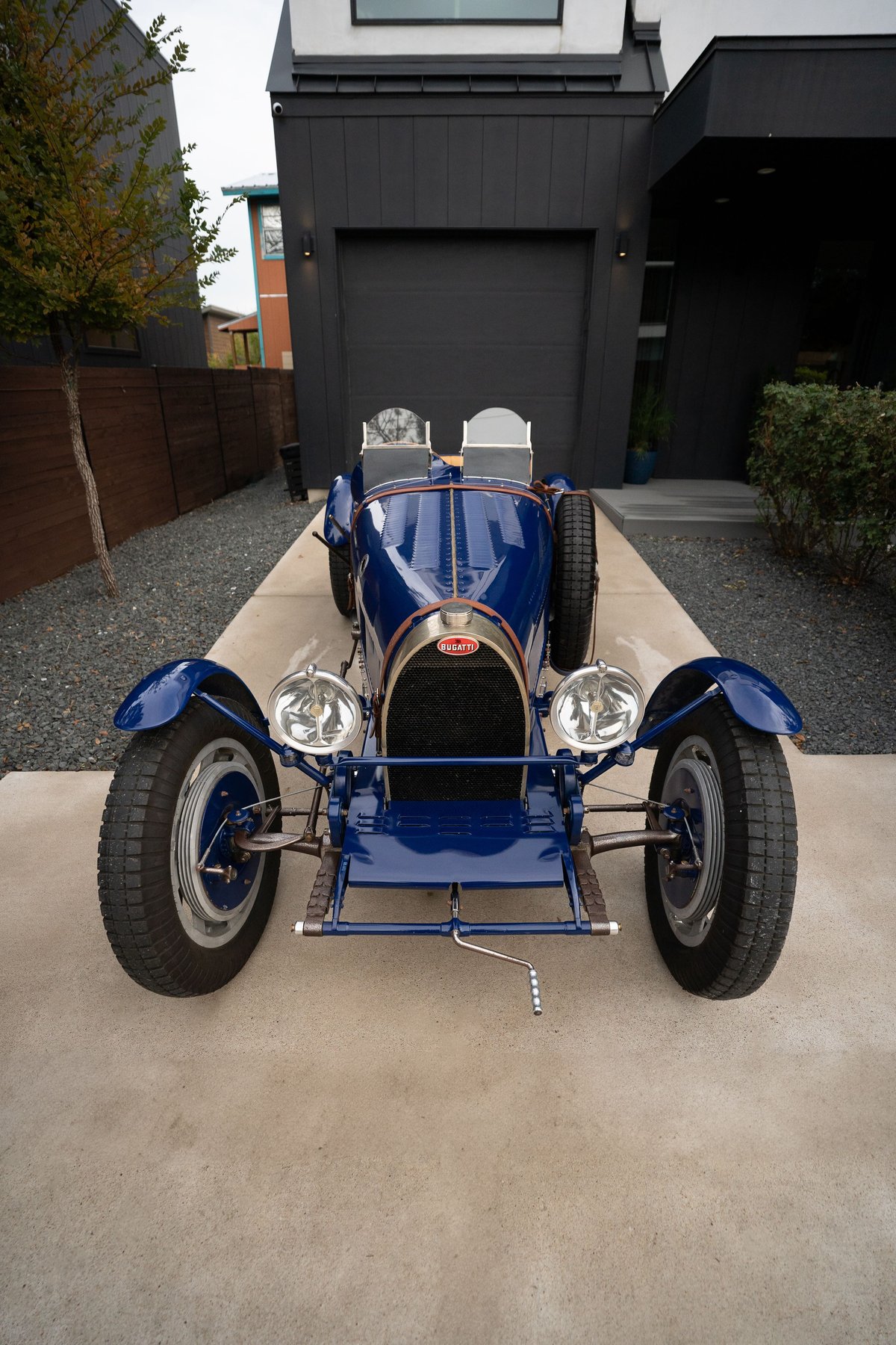 Front view of a blue 1927 Pur Sang Bugatti Type 35 with dual seats, spare tire, and spoked rims.