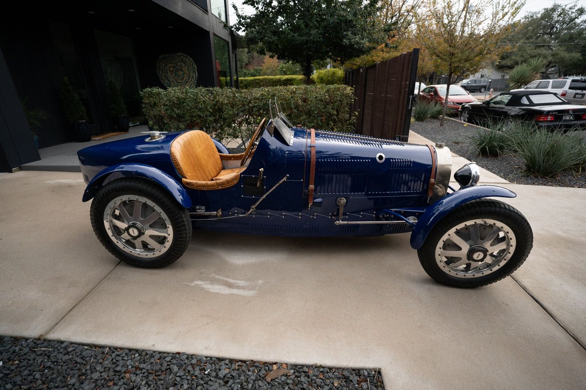 1927 Pur Sang Bugatti Type 35 in deep blue with tan leather seats and intricate silver rims.