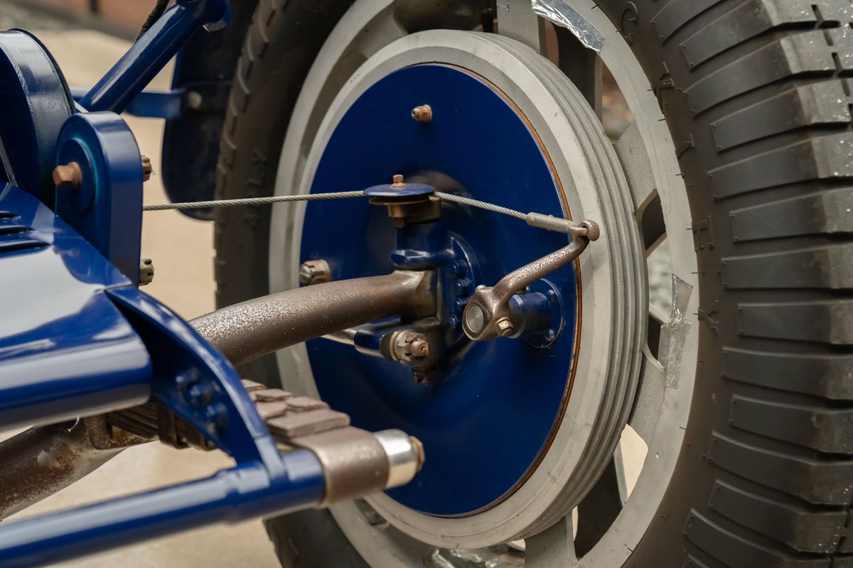 Close-up of a blue 1927 Bugatti Type 35 wheel, showing brake drum, suspension, and tire.