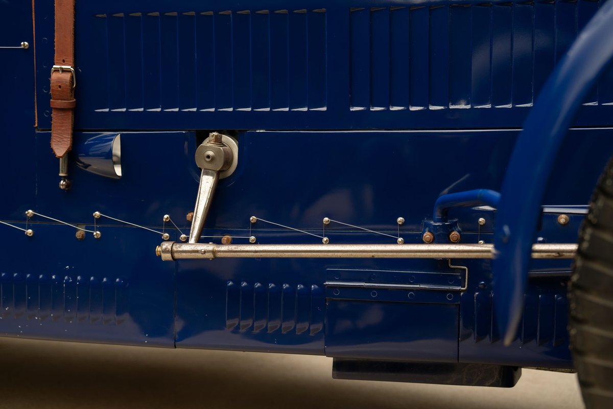 Close-up of the blue 1927 Bugatti Type 35 Pur Sang's side door with leather strap and chrome trim.