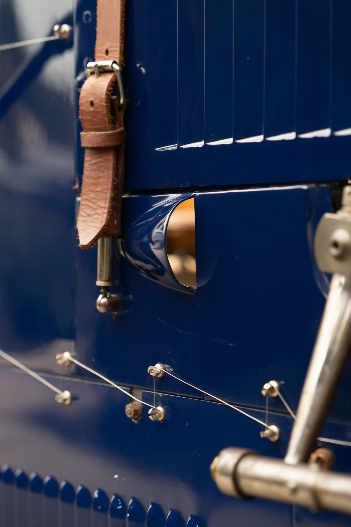 Detail of a blue 1927 Bugatti Type 35 with leather strap, louvers, and bracing wires.