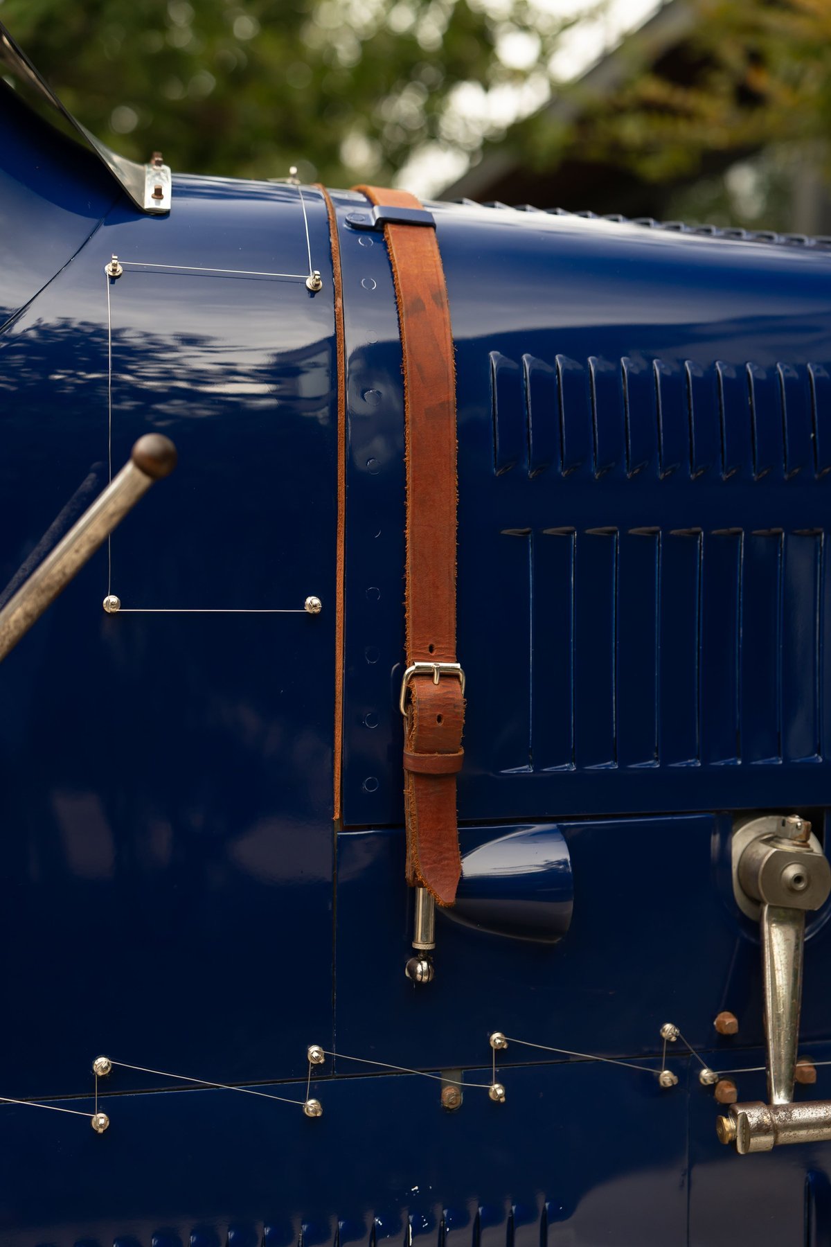 Close-up on the blue 1927 Bugatti Type 35's louvred fender with a leather hood strap.