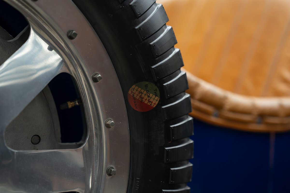 Close-up of a Bugatti Type 35 tire with a vintage "Bugatti Automobiles" sticker on the sidewall and a polished rim.