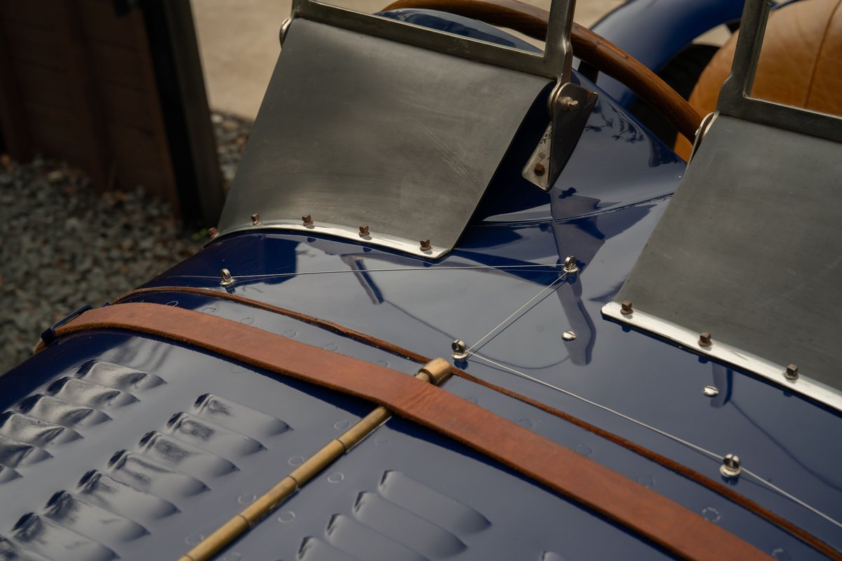 Close-up of the dark blue 1927 Bugatti Type 35 hood, showing leather straps and metal trim.