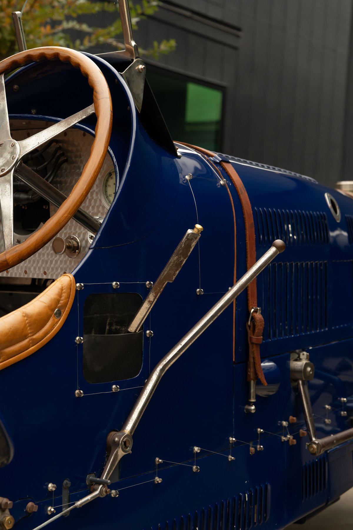 Close-up of a blue 1927 Bugatti Type 35, showing leather trim, wooden steering wheel, and metal levers.