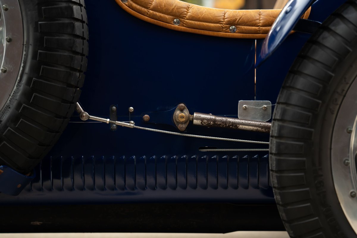 Close up of a vintage blue Bugatti Type 35 showing spare tire, chrome trim, and leather interior.