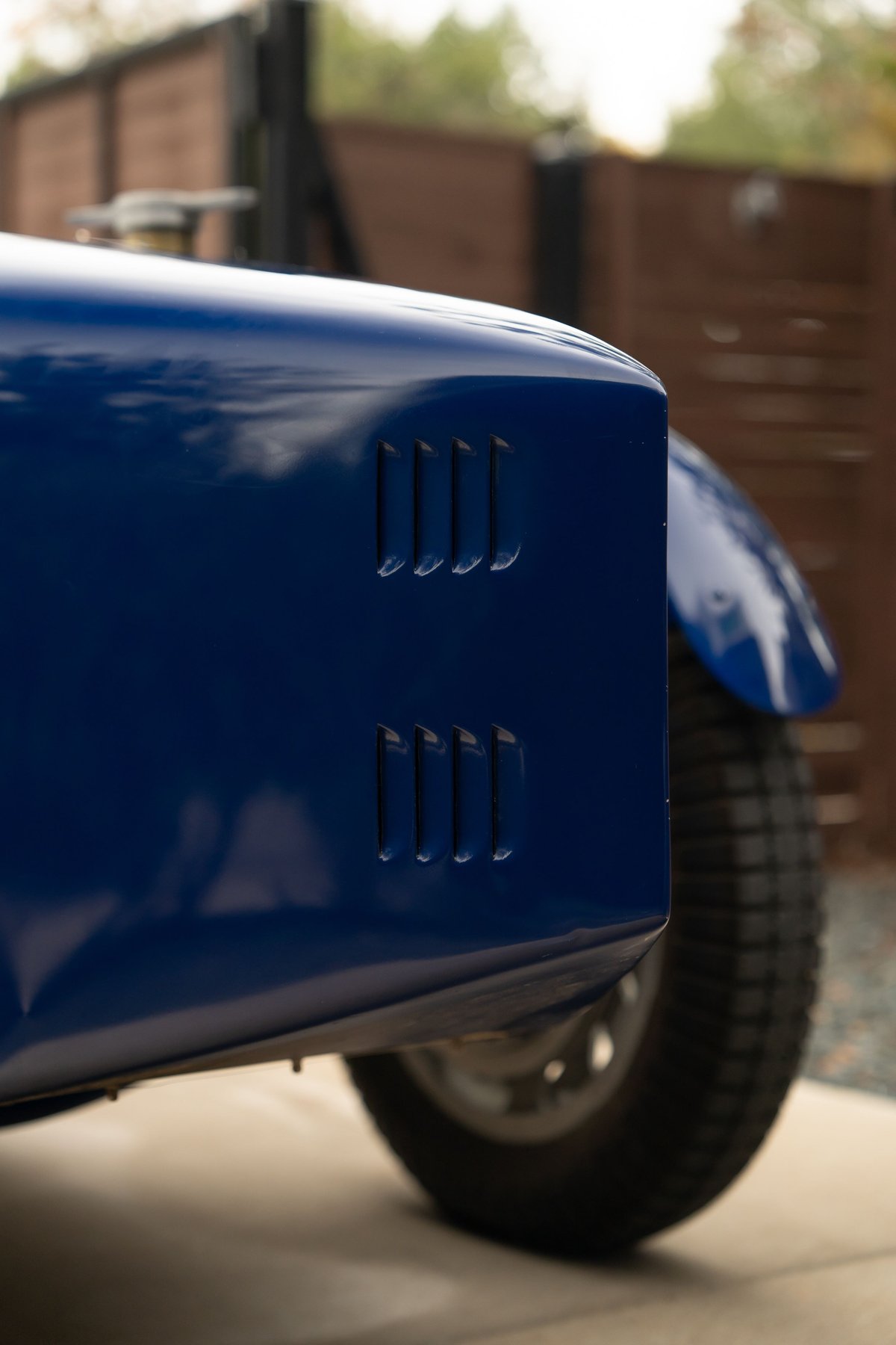 Close-up of a blue 1927 Bugatti Type 35 showing vent details on the fender and wheel.