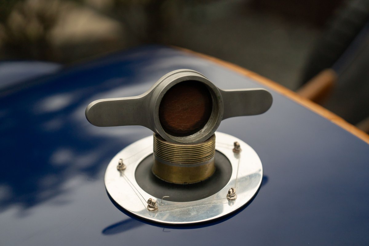 Close-up of a vintage Bugatti Type 35's chrome cap and winged nut on a deep blue body.