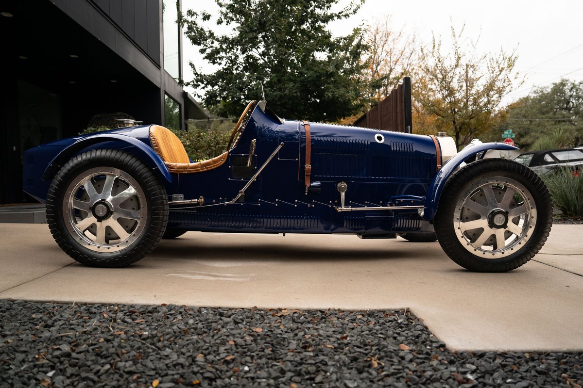 Blue 1927 Pur Sang Bugatti Type 35, featuring tan leather seats, chrome spokes rims, and vintage body trim.