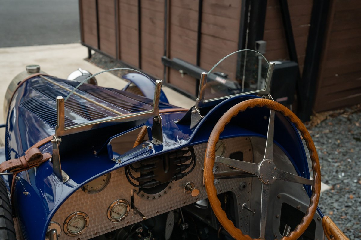 Close-up of a blue 1927 Pur Sang Bugatti Type 35 dashboard and wooden steering wheel.