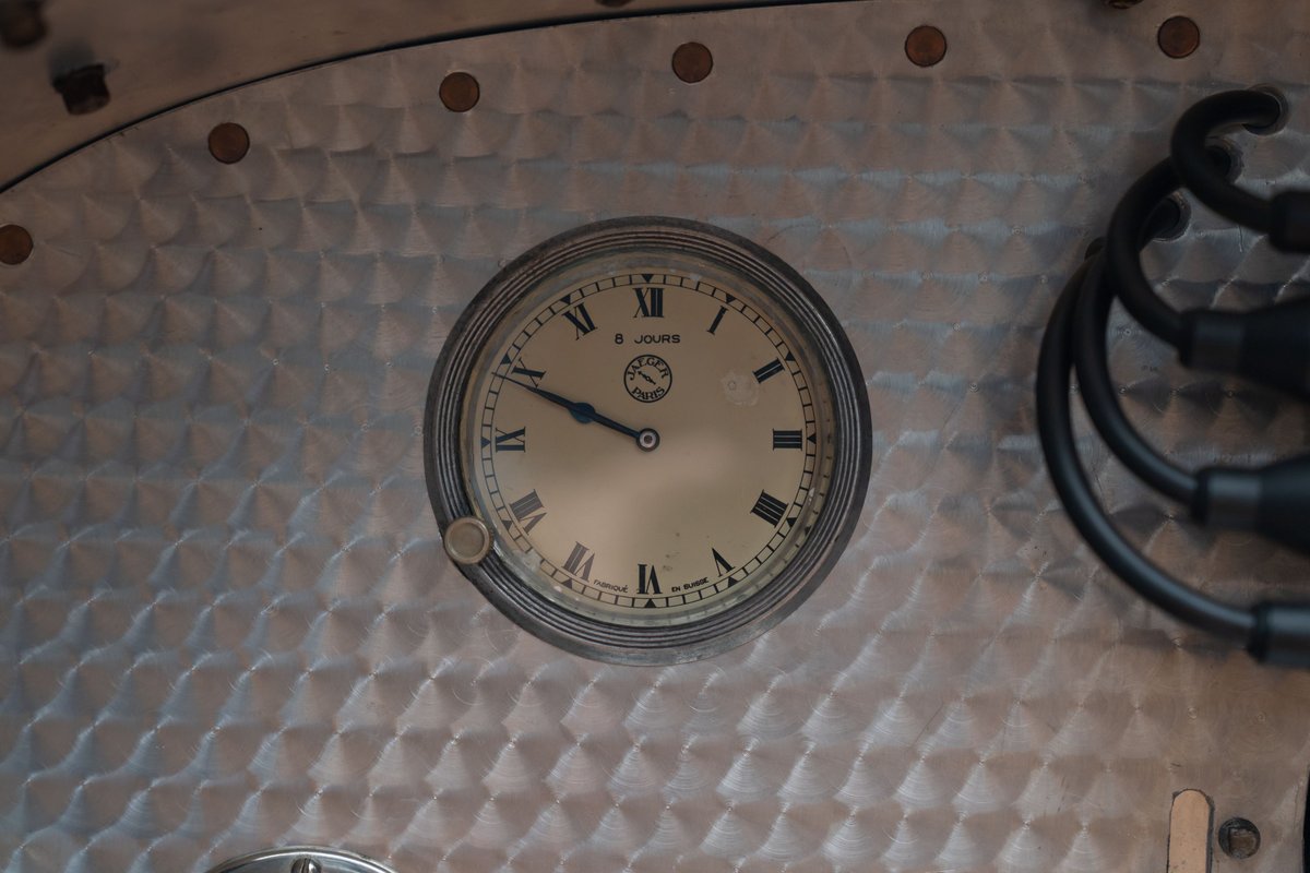 1927 Bugatti Type 35 Pur Sang dashboard clock with Roman numerals on brushed metal.