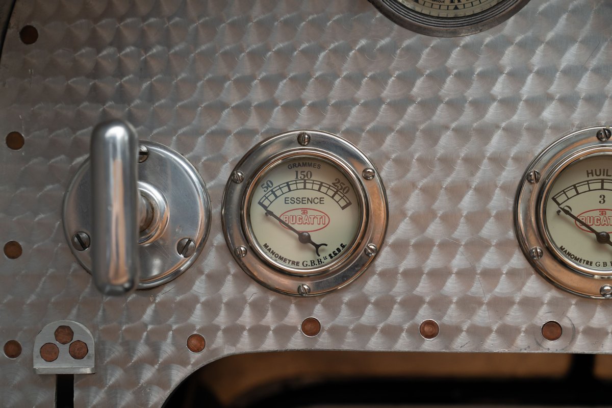 Vintage Bugatti Type 35 dashboard gauges with silver trim and a brushed metal finish.