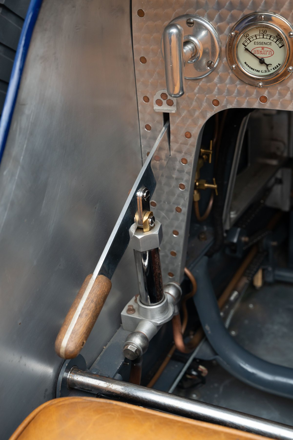 Close-up of a vintage Bugatti Type 35 cockpit, showing a wooden lever and a gauge.