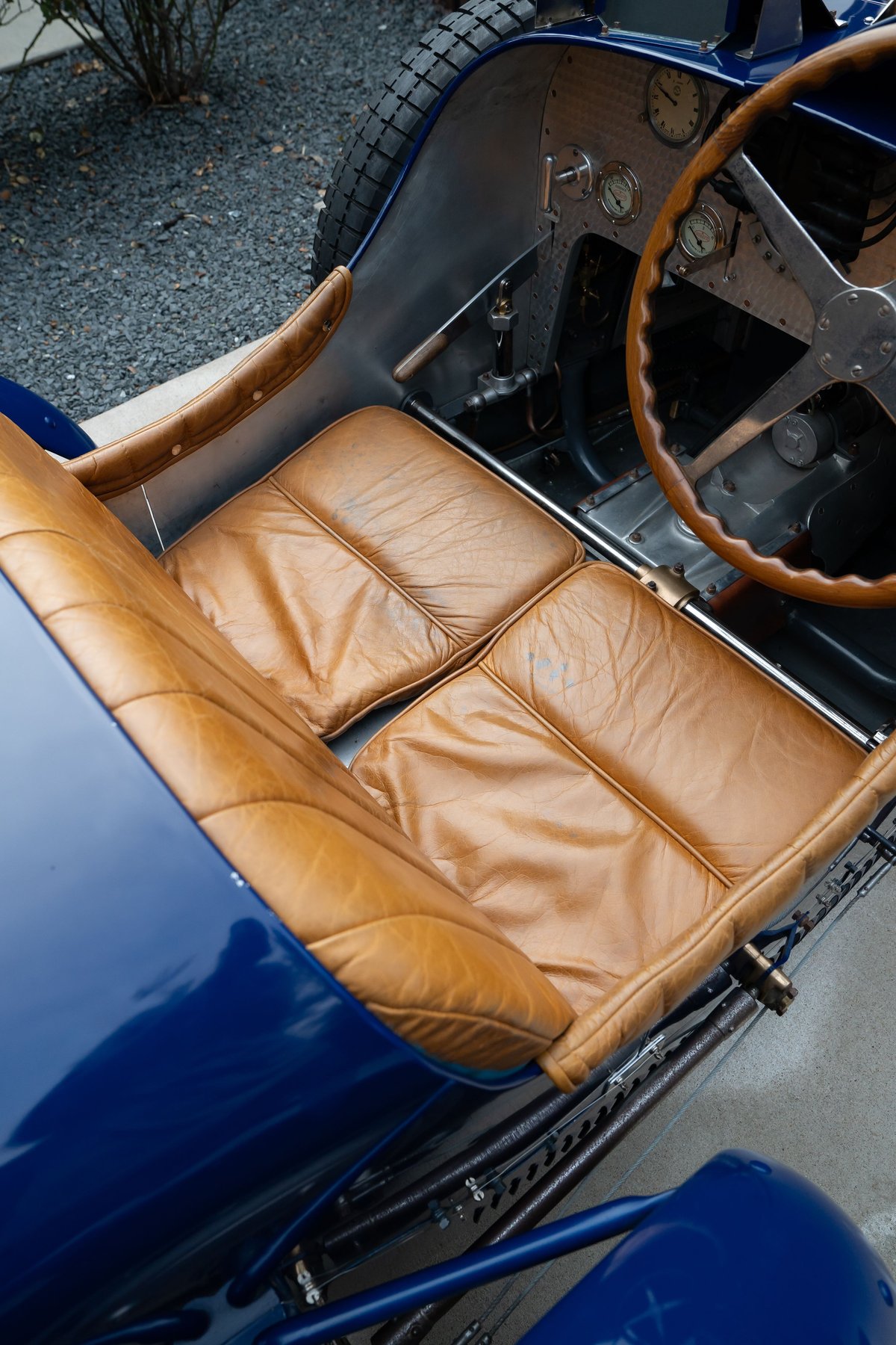 Close-up of tan leather seats in a blue 1927 Bugatti Type 35, showing dashboard, steering wheel.