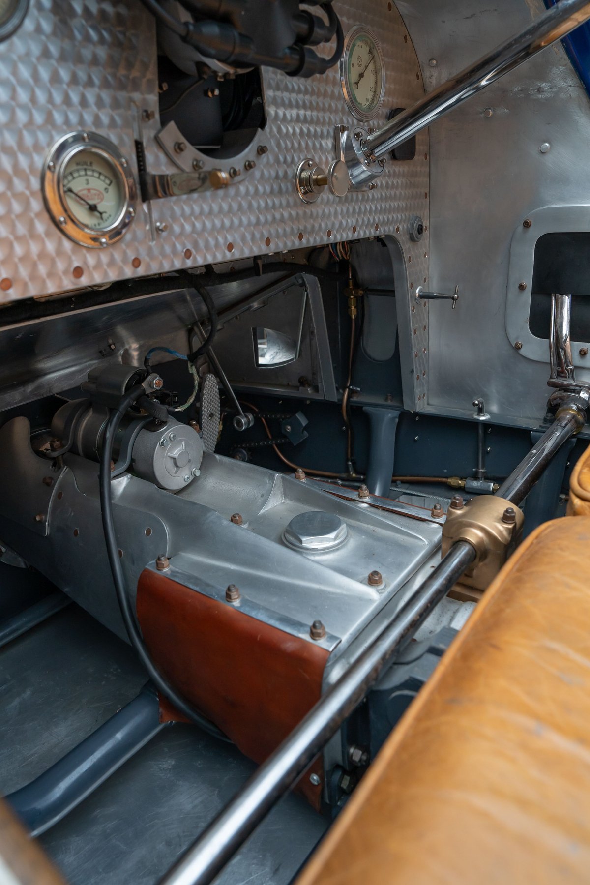 Close-up of a 1927 Bugatti Type 35's riveted metal dashboard, gauges, and engine compartment.