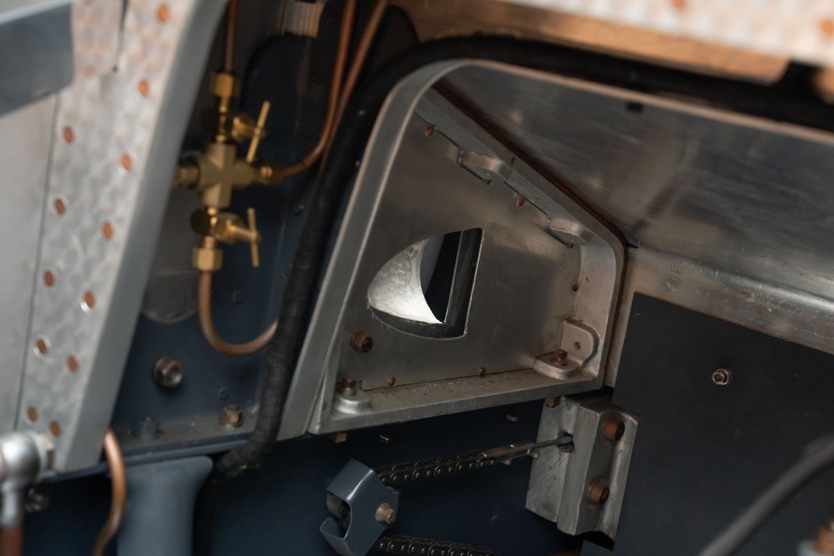 Vintage Bugatti Type 35 dash detail with brass fuel valves and raw aluminum trim.