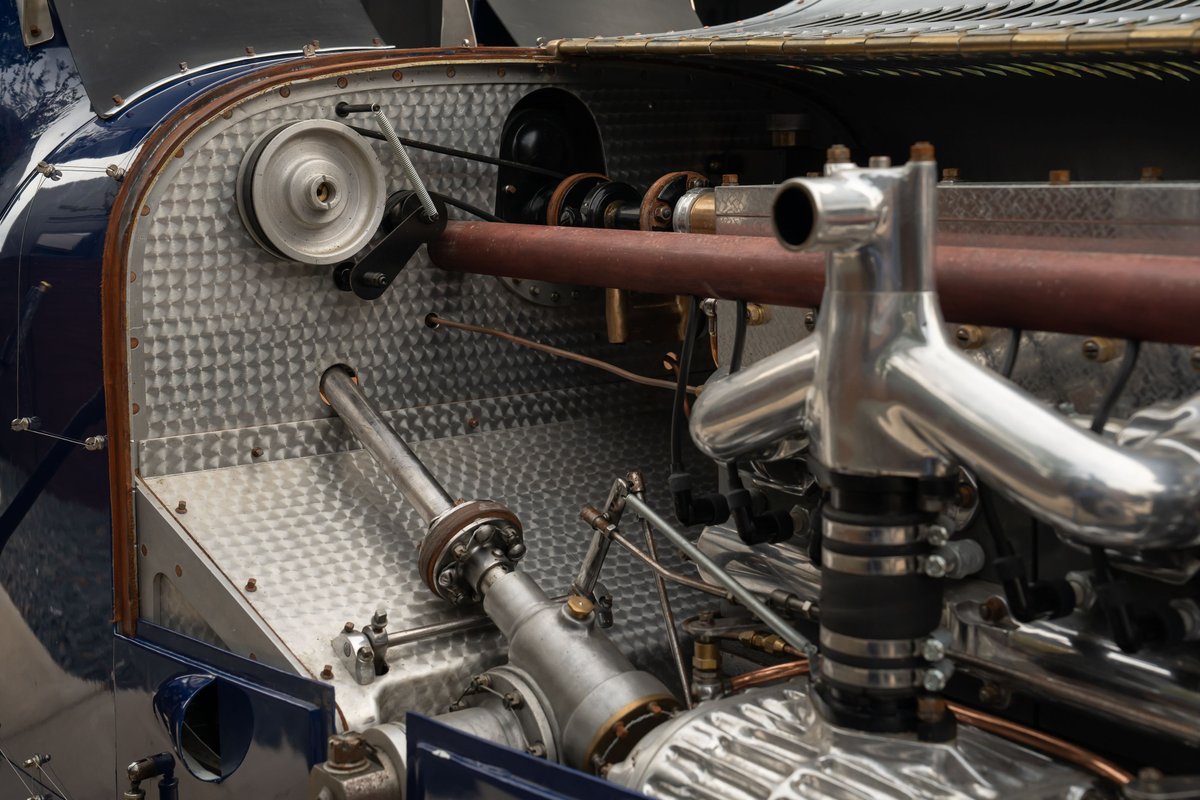 Close-up of the engine bay of a blue 1927 Pur Sang Bugatti Type 35, showing polished metal intake manifold and belt-driven pulley.