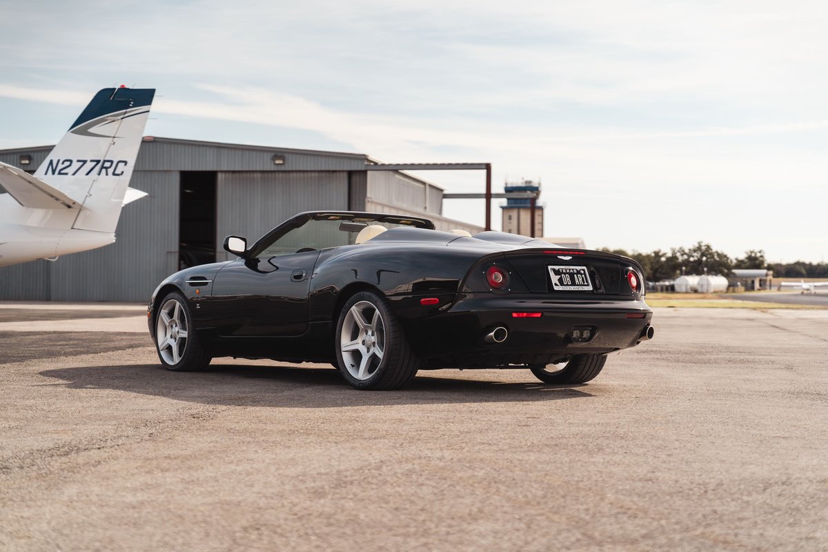 2003 black Aston Martin DBAR1 Zagato convertible with silver rims on an airport tarmac.